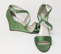 A pair of sage green wedding shoes with high wedge and straps across the front of the foot 