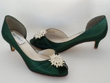 A pair of hunter green satin kitten heels with a peep toe and designed with a crystal design on the front of the shoes