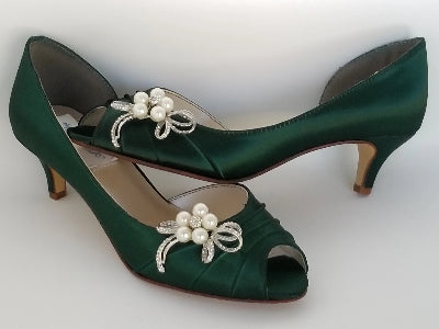 A pair of hunter green satin kitten heels with a peep toe and designed with a crystal and bow design on the side of the shoes