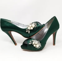 A pair of high heeled hunter green satin shoes with a peep toe and a hidden platform at the front of the shoes and a pearl and crystal design on the front of the shoes
