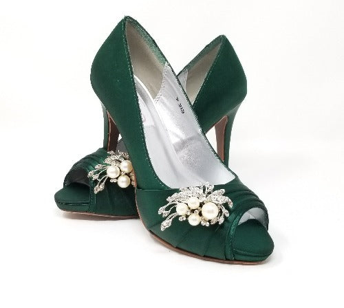 A pair of high heeled hunter green satin shoes with a peep toe and a hidden platform at the front of the shoes and a pearl and crystal design on the front of the shoes
