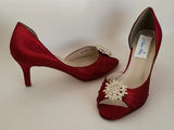 A pair of red satin medium height heel shoes with a peep toe and designed with a crystal design on the front of the shoes
