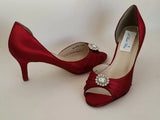 A pair of red satin medium height heel shoes with a peep toe and designed with a crystal design on the front of the shoes