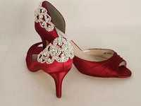 A pair of red satin medium height heel shoes with a peep toe and designed with a crystal design on the back heel of the shoes