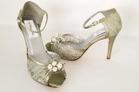 A pair of sage green high heeled platform lace shoes with an ankle strap and a crystal and pearl design on the front of the peep toe shoe