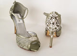 A pair of sage green high heeled platform lace shoes with an ankle strap and a crystal design on the front of the peep toe shoe and a crystal design on the back heel of the shoes