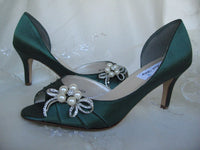 A pair of hunter green satin medium height heel bridal shoes with a peep toe and designed with a crystal and pearl design on the side of the shoes 
