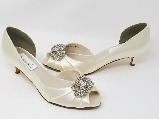 A pair of  ivory satin kitten heels with a peep toe and designed with a crystal design on the front of the shoes