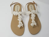 a pair of flat heel ivory bridal sandals with lace and pearls on the straps of the sandals