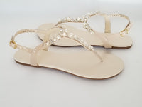 a pair of flat heel ivory bridal sandals with pearls and crystals on the straps of the sandals