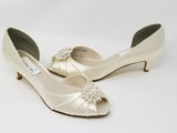 A pair of  ivory satin kitten heels with a peep toe and designed with a crystal design on the front of the shoes
