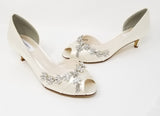 a pair of ivory low heels with a peep toe front and a crystal vine design across the front and side of the shoes