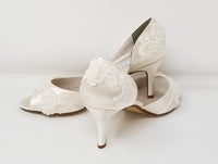A pair of ivory satin medium height heel shoes with a peep toe and designed with ivory lace and pearls on the front and back of the shoes