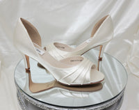 A pair of ivory satin medium height heel shoes with a peep toe