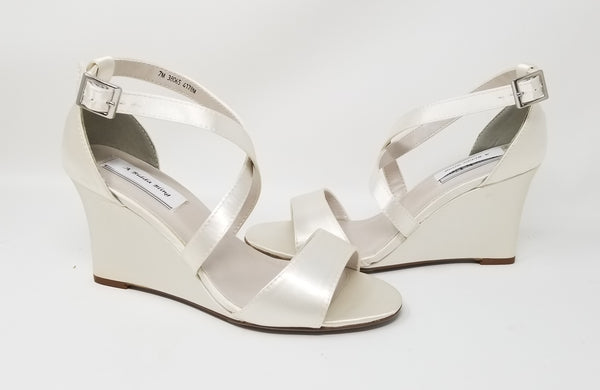 A pair of ivory wedding shoes with high wedge and straps across the front of the foot 