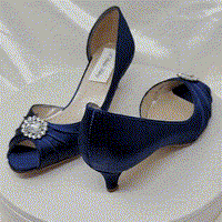 A pair of navy blue satin kitten heel shoes with a peep toe with a small crystal design on the front of the shoes