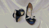 A pair of  bridal shoes in navy blue satin with a kitten heel and a peep toe and a crystal and pearl design on the front and back heel of the shoes