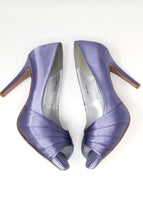 A pair of high heeled lilac purple satin shoes with a peep toe and a hidden platform at the front of the shoes 