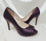 A pair of high heeled eggplant satin shoes with a peep toe and a hidden platform at the front of the shoes 