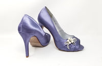 A pair of high heeled lilac purple satin shoes with a peep toe and a hidden platform at the front of the shoes and a pearl and crystal design on the side of the shoes
