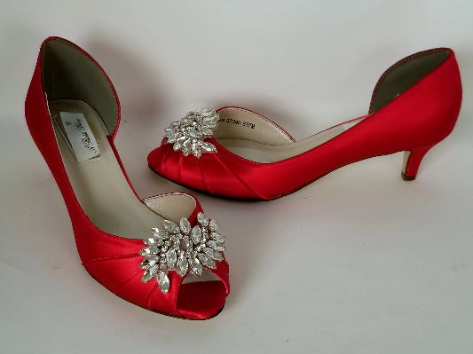 A pair of red satin kitten heels with a peep toe and designed with a crystal design on the front of the shoes