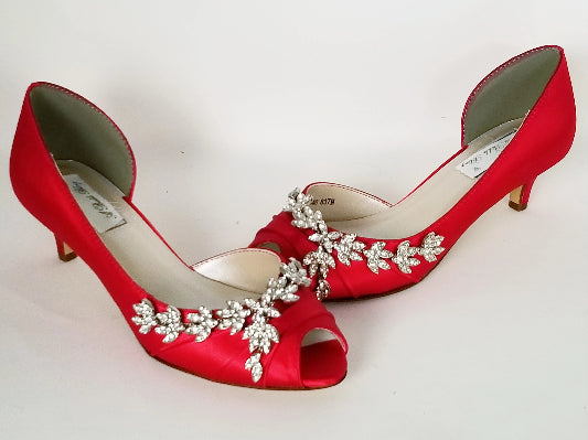 A pair of red satin kitten heel shoes with a peep toe and a crystal vine design on the front and side of the shoes