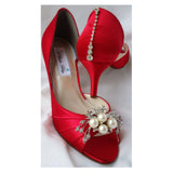 A pair of red satin medium height heel shoes with a peep toe and designed with a crystal design on the front of the shoes and a crystal design on the back heel of the shoes