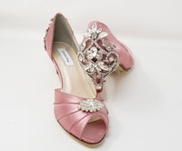 A pair of dusty rose satin kitten heels with a peep toe and designed with a crystal design on the front of the shoes and a crystal design on the back heel of the shoes