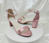 A pair of dusty rose block heel shoes with an ankle strap 