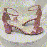 A pair of dusty rose block heel shoes with an ankle strap 