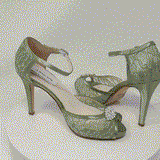 A pair of sage green lace high heeled shoes with a front hidden platform and an ankle strap with a peep toe and a front crystal design