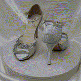 A pair of silver high heeled platform lace shoes with an ankle strap and a crystal design on the front of the peep toe shoes