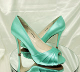 A pair of high heeled aqua blue satin shoes with a peep toe and a hidden platform at the front of the shoes 