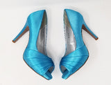 A pair of high heeled turquoise satin shoes with a peep toe and a hidden platform at the front of the shoes 